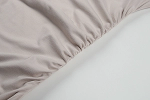 Détail du tissu en maille fine et de la couture froncée sur cette robe d'été beige