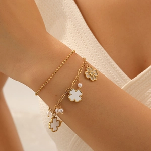 Close-up of gold double-layer chain bracelet with white flower charms and elegant pearls