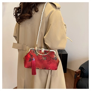Detail of red vintage silk handbag with pearl chain and tassel on model's coat
