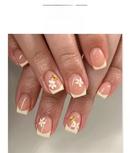 Macro detail of French tip nails featuring delicate white flowers and yellow bees
