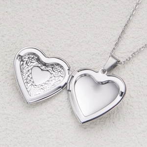 Polished silver heart locket pendant necklace with intricate floral pattern inside