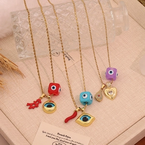 Flat lay of gold eye pendant necklaces with red chili and feather charms on a tray