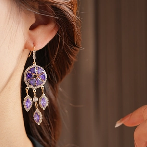 Close-up of vintage gold tassel earrings with purple gemstones worn by a model