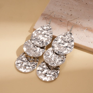 Détail de boucles d'oreilles goutte d'argent avec surfaces en métal martelé et crochets