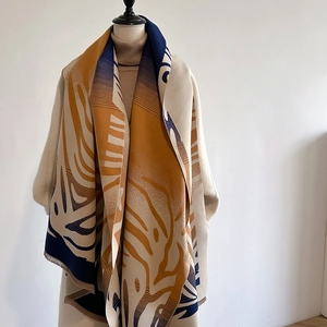 Elegant beige cashmere-like scarf with abstract yellow and navy leaf pattern on a mannequin