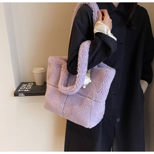 Detaillierte Makroansicht der lila Lammfell-Tasche mit Webmuster und süßem Anhänger