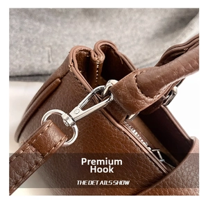 Detailed close-up of premium silver metal hook and litchi texture brown leather strap