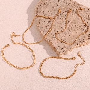 Detailed view of four 18K gold plated stainless steel box and link chains on beige stone