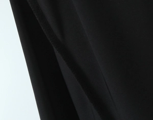 Close-up of the professional stitching and smooth black chiffon fabric on a dress hem