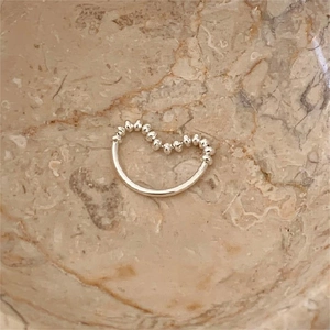 Minimalist 925 sterling silver beaded wave ring shown on a textured marble background