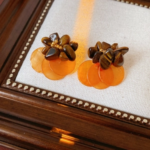 Close-up of vintage earrings featuring tiger eye stones and orange shell discs