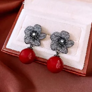 Vintage flower earrings with silver needles, zircons, and red pearl pendants in a jewelry box