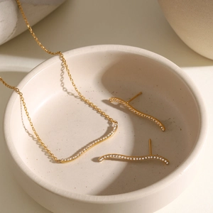 Detail of 18k gold plated wavy necklace and earring set with shimmering rhinestones