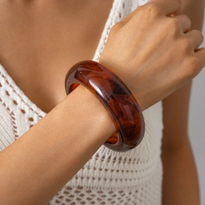 Close-up of a wide amber resin geometric bangle with tortoiseshell pattern on wrist