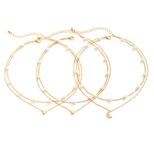 Close-up of triple layered gold pearl necklaces with star, heart and moon pendants