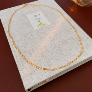 Detailed macro view of gold flat chain necklace texture on premium fabric background