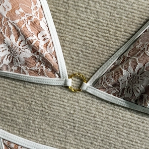 Macro shot of white lace over orange fabric with a golden metal ring connector
