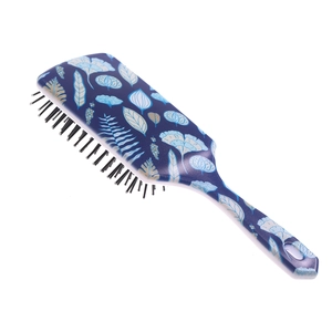 Detail of blue floral hairbrush with golden leaves and black plastic massage bristles
