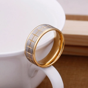 Close-up of tire tread pattern ring with brushed gold and silver finish on a white cup