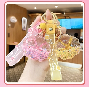 Detail of shell-shaped liquid sand keychain with pink and yellow glitter and silicone strap