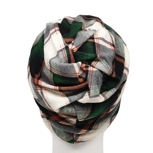 Detail of classic knit plaid pattern in forest green, black and orange on a versatile beanie