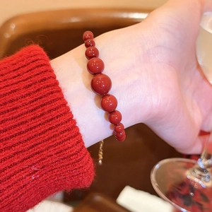 Detailaufnahme eines vintage roten Achat-Perlenarmbands getragen zu einem roten Strickpullover.