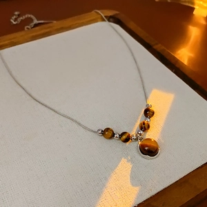 Detailed view of round tiger eye stone pendant on elegant silver chain with bead accents
