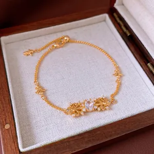 Elegant gold iris flower bracelet with zircon stone on a wooden jewelry box interior