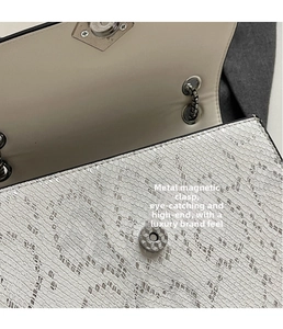Close-up of white snake pattern leather texture with silver magnetic snap closure