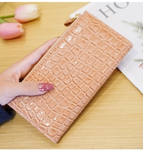 Detail of salmon pink long wallet with stone texture and golden zipper held by a model