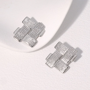 Detail of silver stud earrings featuring a unique woven texture on a white background