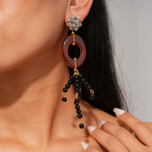 Gros plan de boucles d'oreilles pendantes en résine avec cristaux et pompons noirs