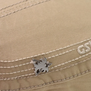 Close-up of khaki cotton twill cap featuring GS embroidery and eagle metal buckle