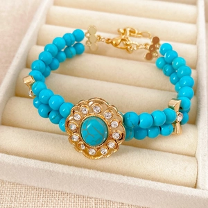 Détail d'un bracelet vintage avec perles turquoise et pendentif fleur en strass