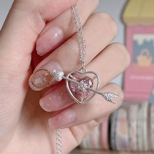 Pink heart cupid arrow necklace with silver chain shown as a worn closeup style