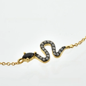 Detailed close-up of golden snake chain bracelet with sparkling zircon and black stone