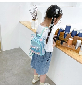 Girl wearing blue holographic sequin backpack with bunny ears and glitter details