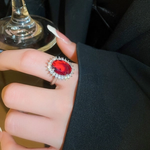 Detailed close-up of a silver ring with a red oval gemstone and sparkling zircon accents