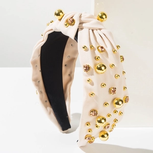 Macro shot of cream knotted headband with golden beads and champagne rhinestones decoration