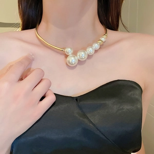 Close-up of elegant gold collar necklace featuring asymmetric white pearls on a model