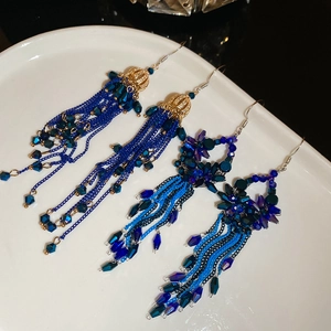 Detail of blue crystal bead flower drop earrings with golden chain tassels on white porcelain