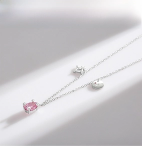 Detail of S925 silver necklace with pink pear-cut stone and Gemini constellation charm
