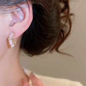 Close-up of C-shaped bamboo earring with pink enamel and crystals on a model