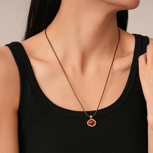 Detail of vintage resin pendant with gold metal frame on a dark brown cord necklace