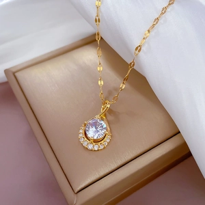 Macro view of teardrop pendant with round center stone on golden lip chain