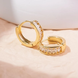 Macro view of gold geometric C-shaped earrings with marquise-cut white zircon accents