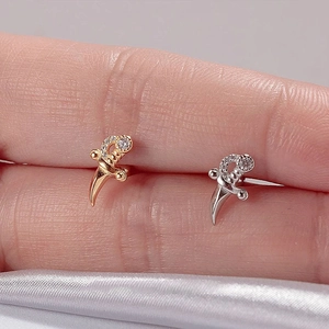 Detailed macro view of gold and silver dagger-shaped earrings with sparkling zircon inlay