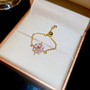 Detail eines verstellbaren Goldrings mit Zirkonia-Blütenblättern auf Seide