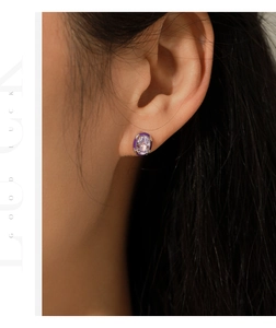 Macro detail of oval purple zircon stud earring with dark enamel border on ear