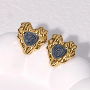 Macro detail of 18K gold-plated heart stud earrings with grey textured centers